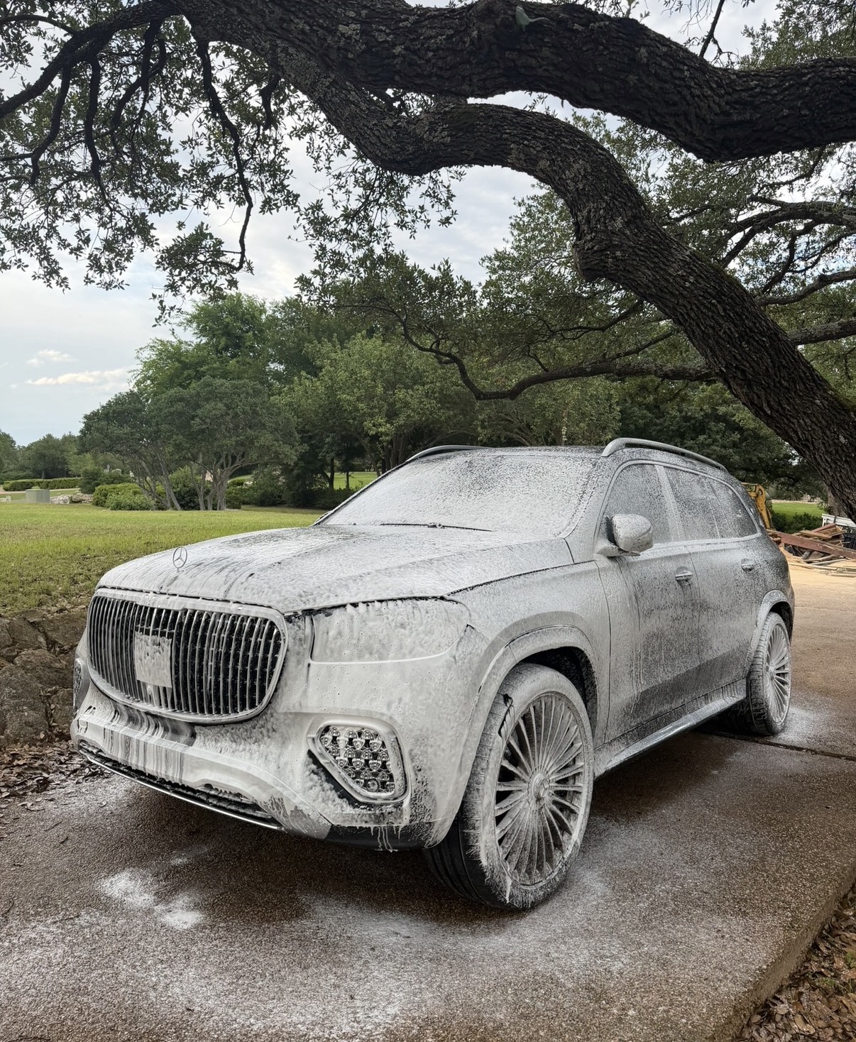 SUV covered in foam being hand washed in a driveway